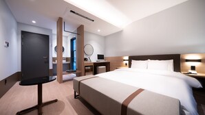 Une chambre d’hôtel moderne équipée d’un grand lit, d’un bureau, d’une chaise, d’une télévision et d’un miroir.