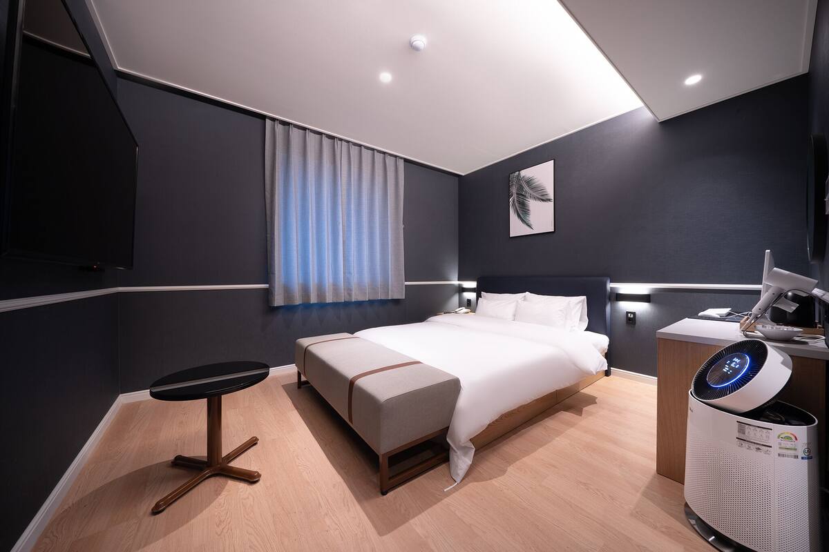 Une chambre d’hôtel moderne équipée d’un lit, d’une table de chevet et d’un bureau avec un ordinateur.