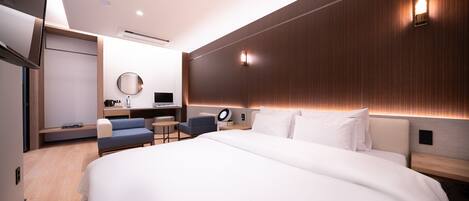 Una habitación de hotel moderna con una cama grande, un escritorio, una silla y un televisor.