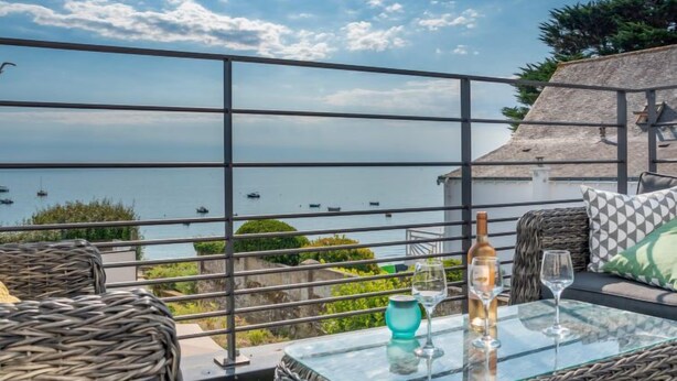 A balcony with wicker furniture, a glass table, and a bottle of wine. - Villa Kerhostin by Interhome (Quiberon)