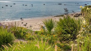 A beach with boats in the water, a sandy shore, and various plants in the foreground. - Villa Kerhostin by Interhome (Quiberon)