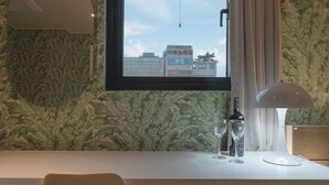 A hotel room with a large window, a table with a bottle and glasses, and a curtain. - Goyo37 Hotel Osan by Anook (Osan)
