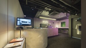 A reception area with a curved desk, a coffee machine, a television, and a sign that reads "goyos hotel". - Goyo37 Hotel Osan by Anook (Osan)