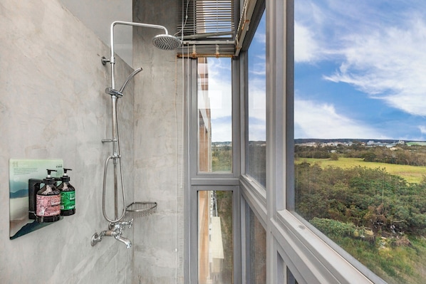 Un baño con ducha, ventana y vistas al campo.