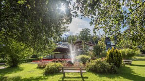 En park med en fontän, en bänk och byggnader i bakgrunden.