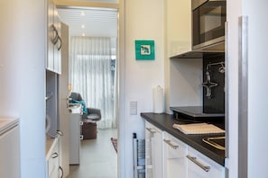 Una cocina moderna con armarios blancos, encimera negra y un microondas.