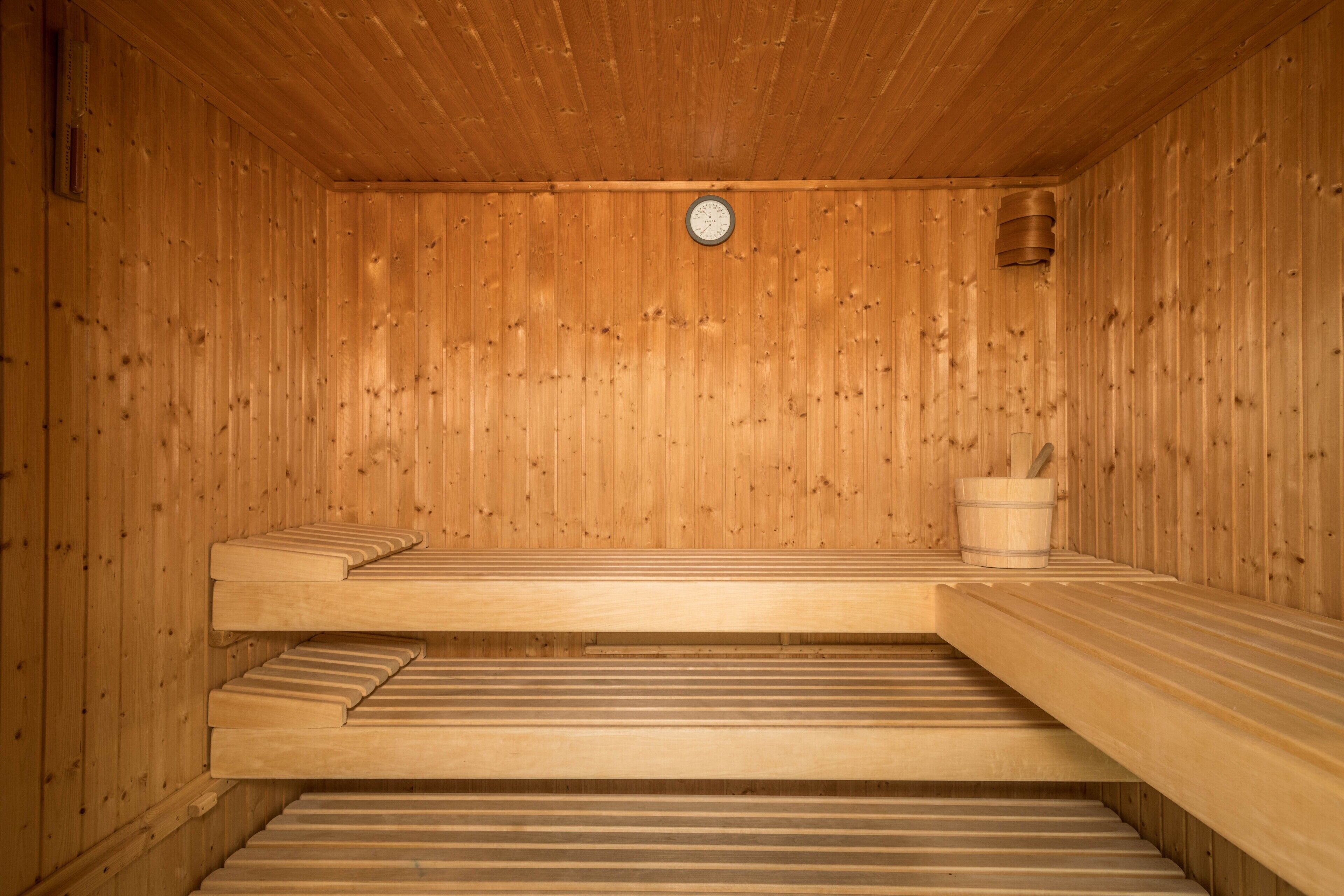 Un sauna avec des bancs en bois et une horloge au mur.