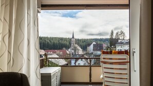 A balcony with a view of a town, including a church and residential buildings.
