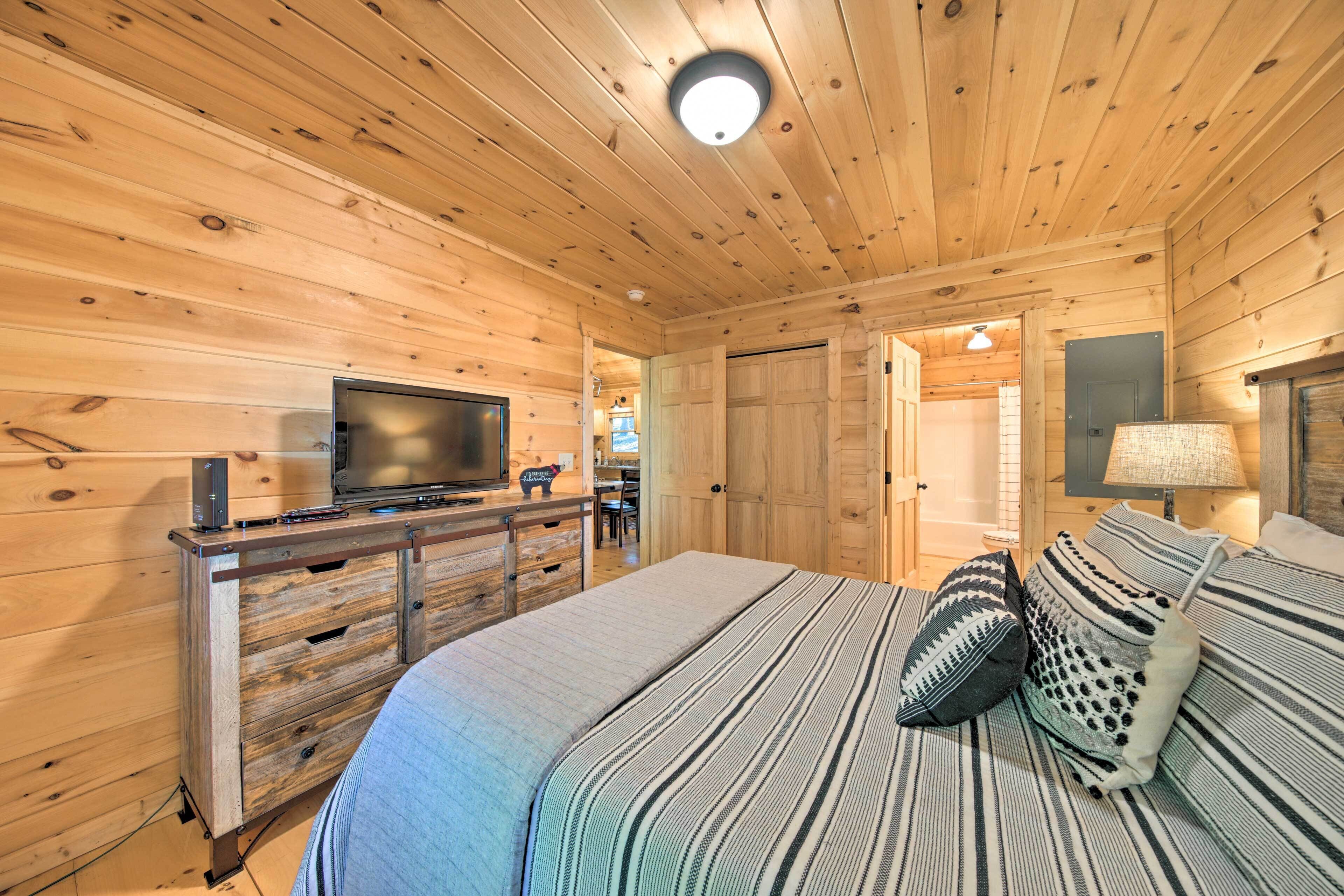 Une chambre à coucher aux murs lambrés, avec un lit, une commode, un téléviseur et une lampe.