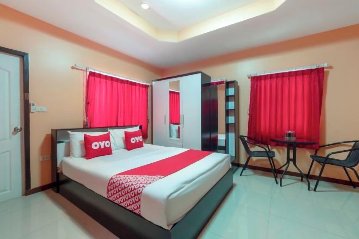 A hotel room with a bed, a desk, and two chairs.