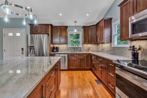 A modern kitchen with wooden cabinets, stainless steel appliances, and a marble countertop. - Break Away - sleeps 12, kayaks, SUP's fire pit, games galore! Great for kids and adults! (Moneta)