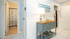 A hallway with a blue cabinet, a lamp, and a painting on the wall.