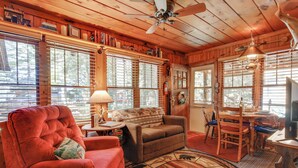 Un intérieur de chalet chaleureux avec une cheminée, des meubles en bois et de grandes fenêtres.