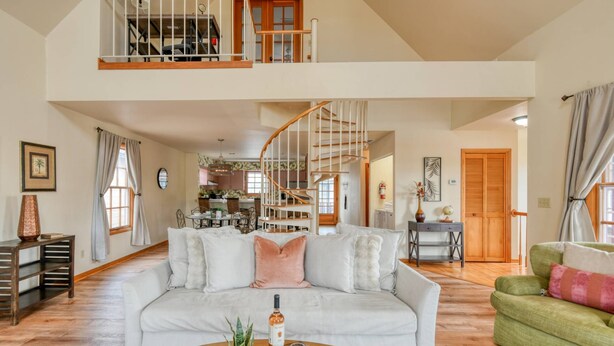 A spacious living room with a high ceiling, a staircase, and a dining area.