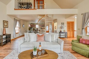A spacious living room with a high ceiling, a staircase, and a dining area.