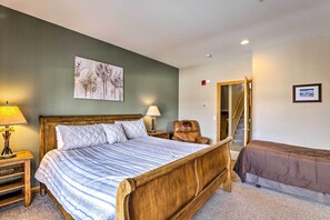 Ein Schlafzimmer mit einem großen Bett, einem Sessel, einem Nachttisch mit Lampe und einem Bild an der Wand.