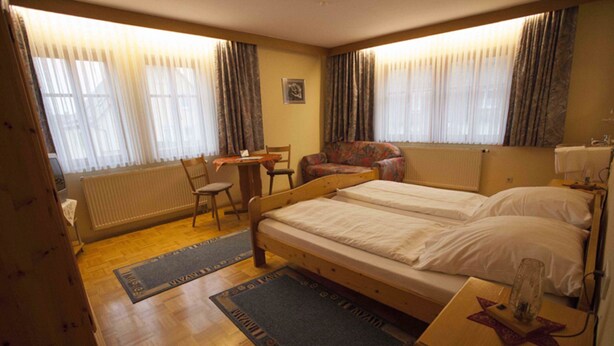 Habitación de hotel con cama doble, escritorio pequeño, silla, sofá y radiador.