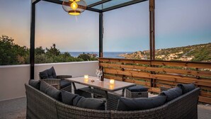 Un balcon agrémenté de meubles en osier, une table avec des bougies et un luminaire suspendu.