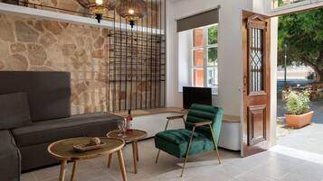 Una sala de estar moderna con una pared de piedra, un sofá, un sillón verde, una mesa de centro y dos lámparas colgantes.