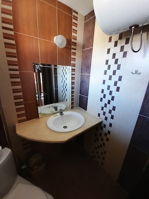 A bathroom with a toilet, sink, and shower.