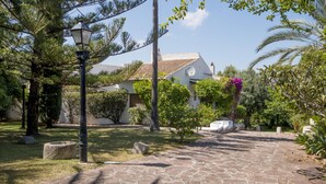 A courtyard with a stone pathway, a lamp post, and a house with a tiled roof.