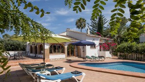 A poolside area with lounge chairs, a table with chairs, and a small pool.