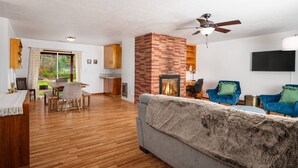 Een moderne woonkamer met een open haard, houten vloeren en een eethoek met een tafel en stoelen.