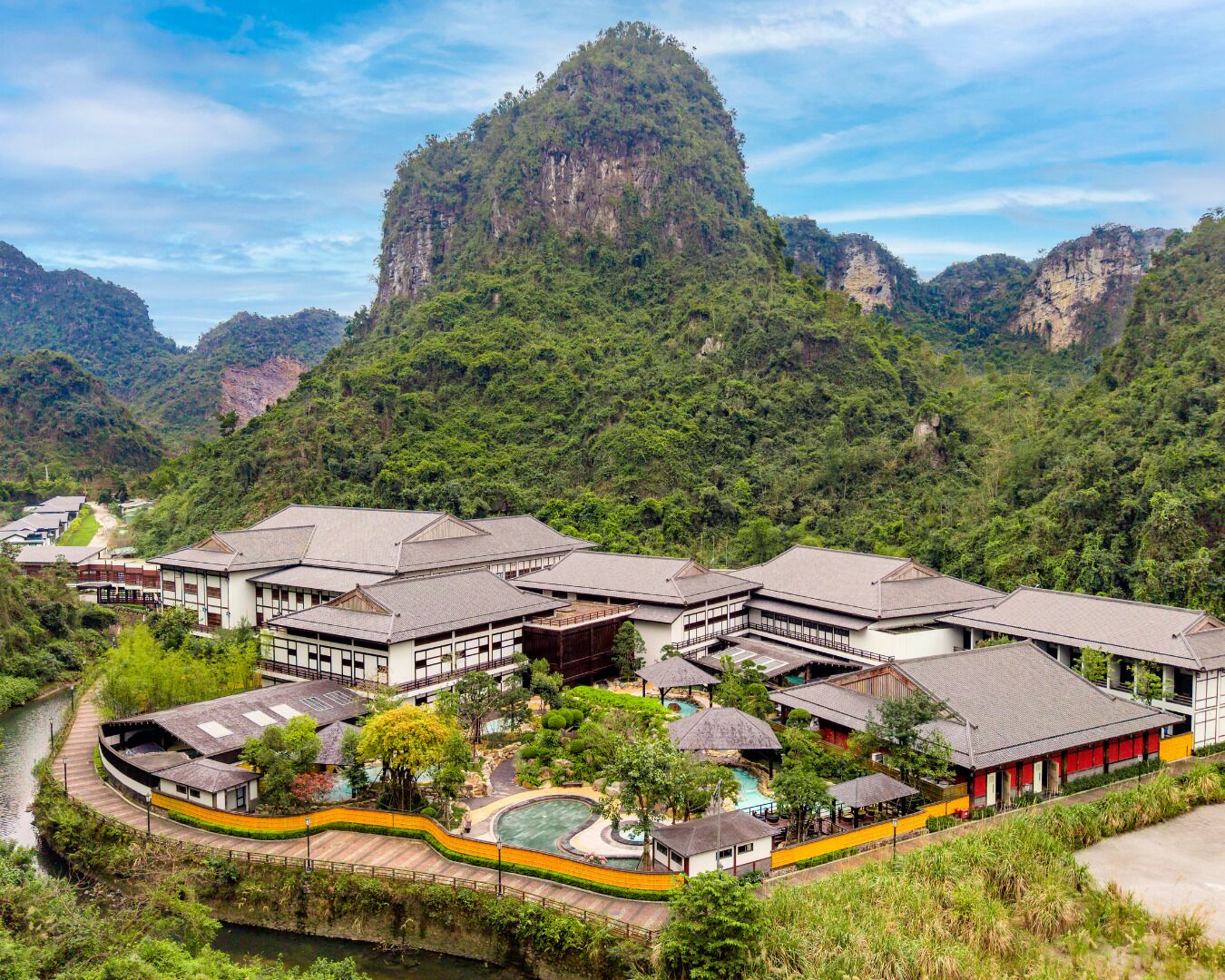 A traditional Japanese ryokan with multiple buildings, a swimming pool, and a river.