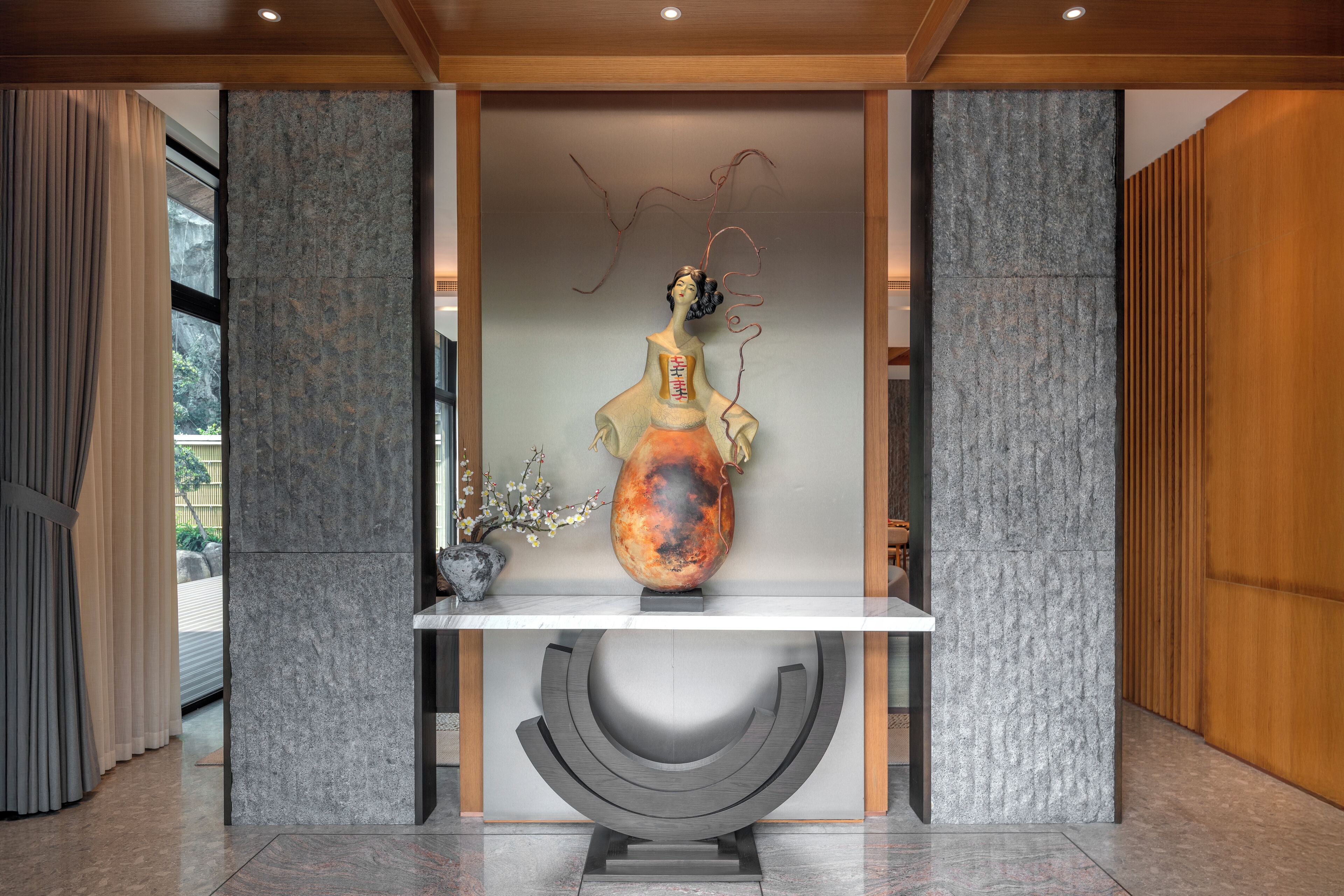 A modern interior with a stone wall, a decorative sculpture, and a wooden panel.
