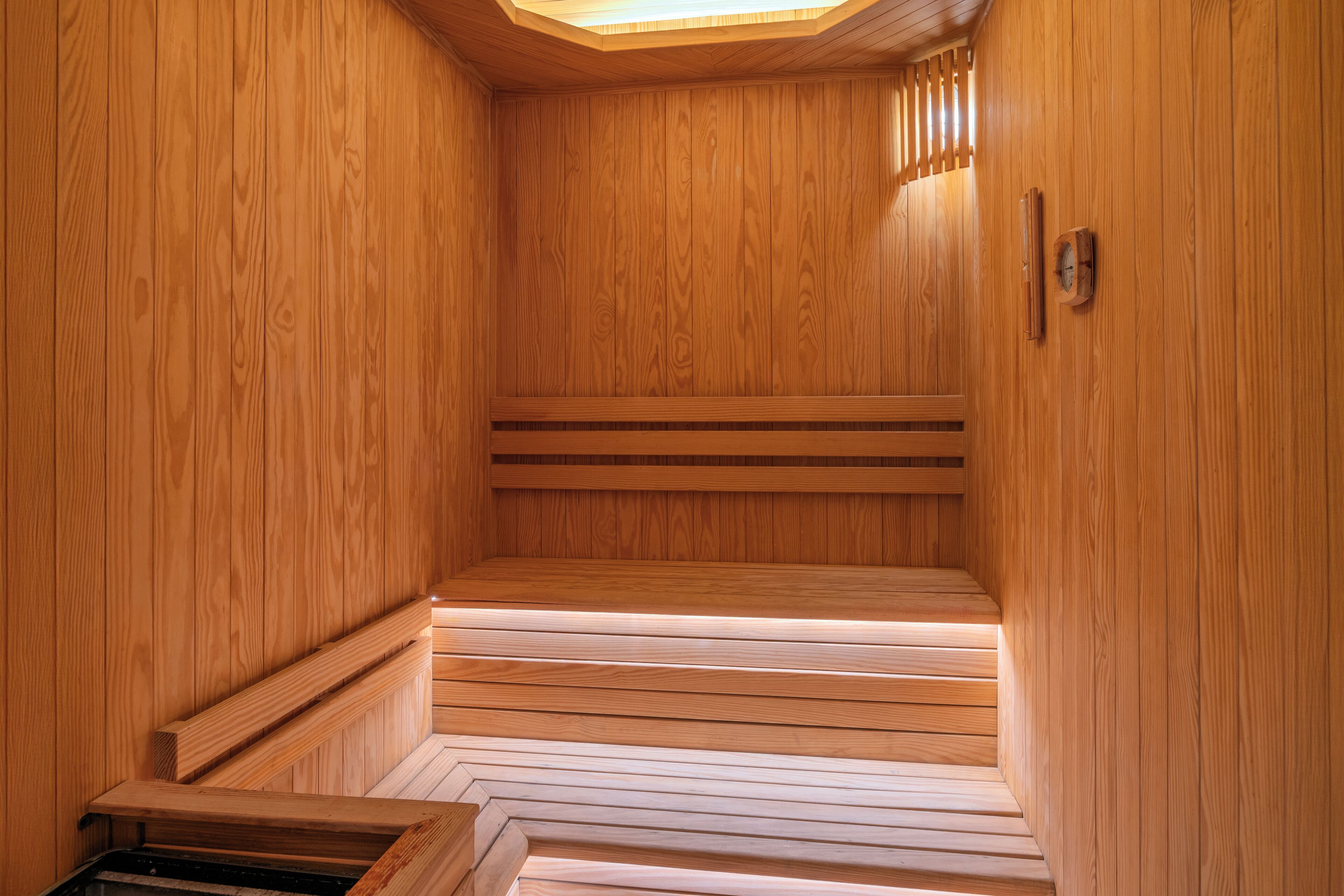 A wooden sauna with benches and a sloped floor leading to a bench at the far end.