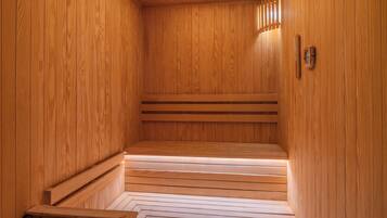 A wooden sauna with benches and a sloped floor leading to a bench at the far end.
