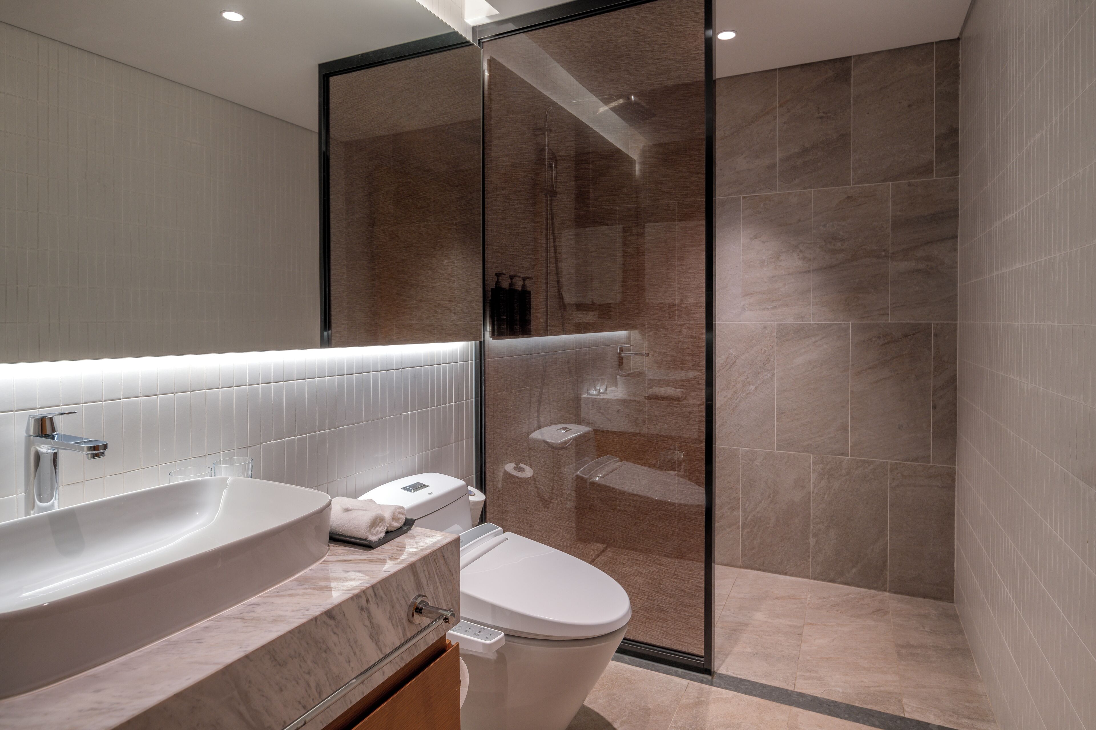 Un baño moderno con un lavamanos grande, inodoro y ducha con mampara de vidrio.