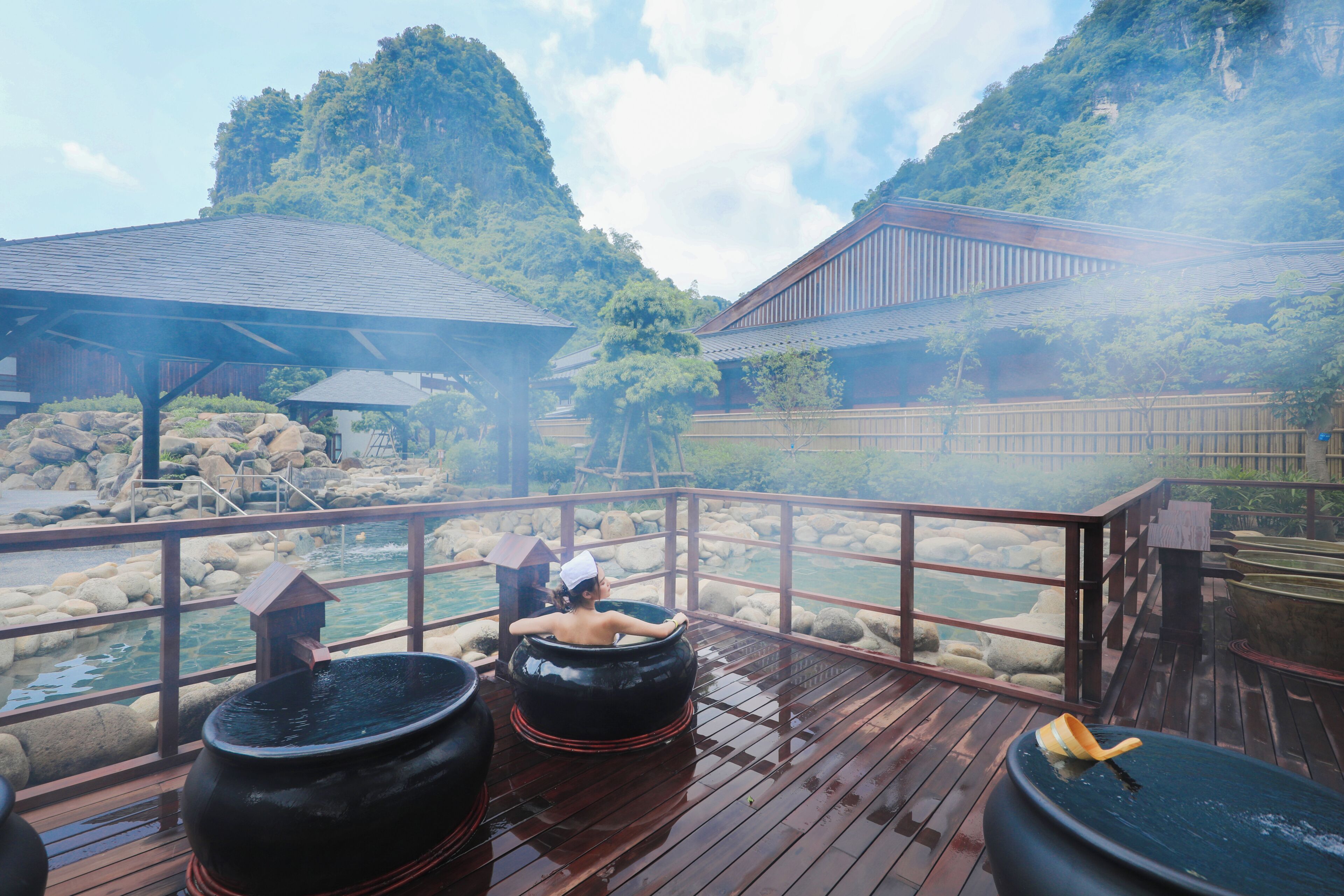 A wooden deck with hot tubs, a wooden structure, and a rocky water feature.