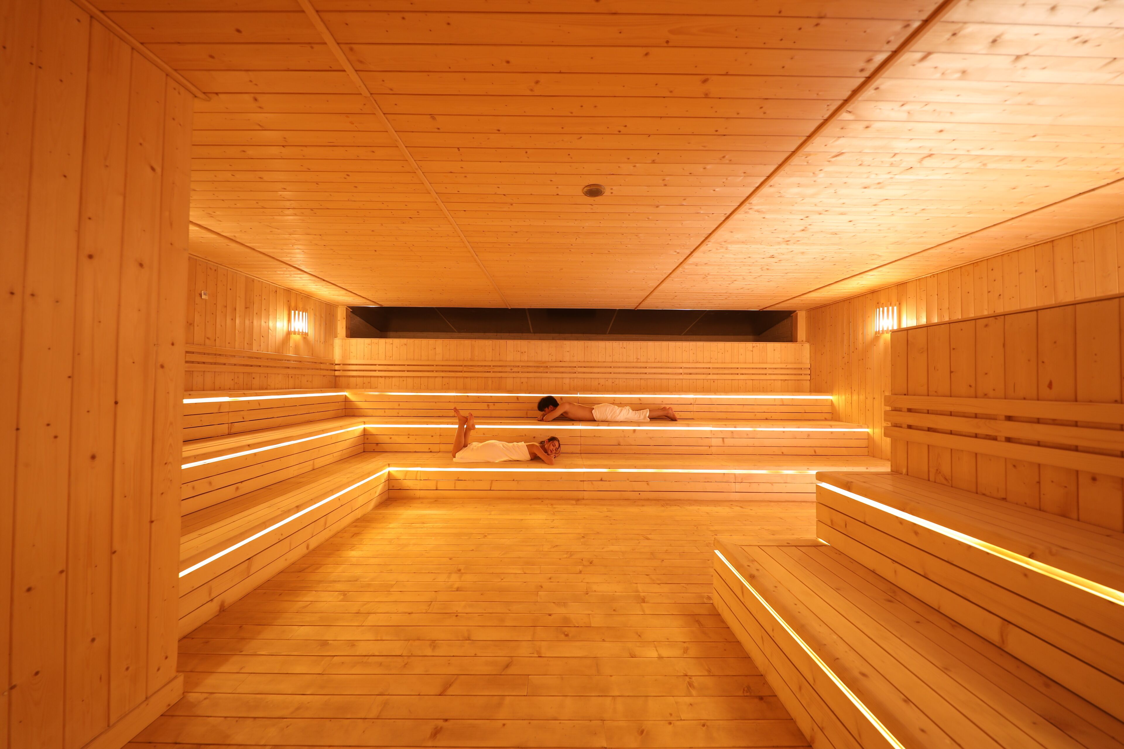 Un sauna avec des bancs en bois et un plancher incliné.