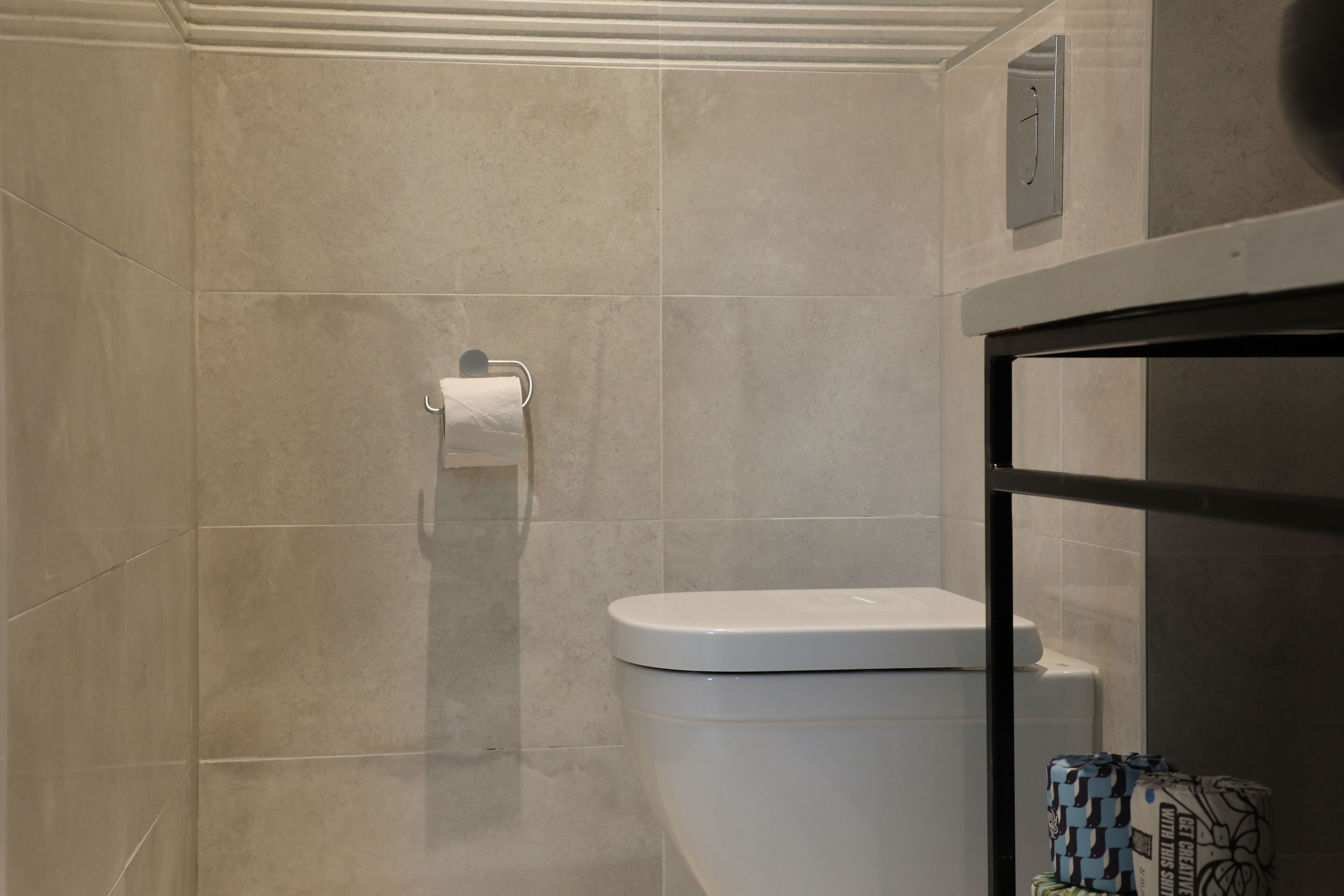 Un baño con inodoro, dispensador de toallas y zona de ducha.