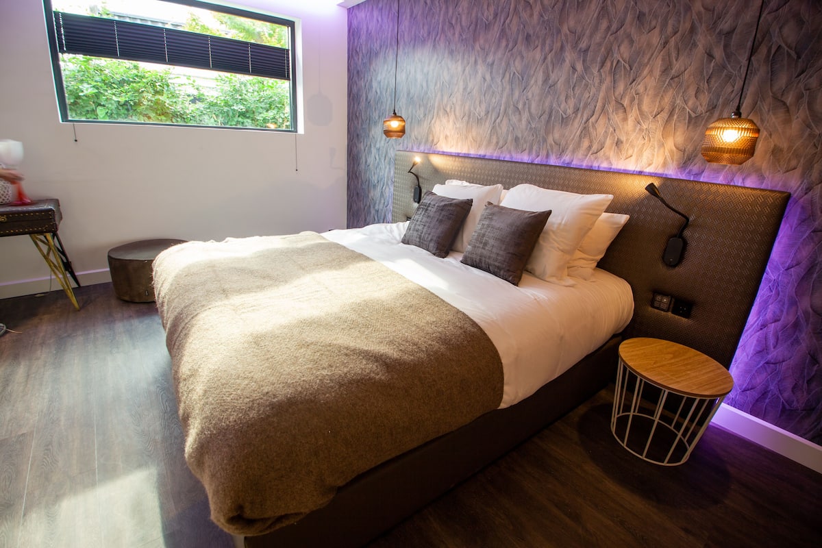 A modern bedroom with a large bed, a bedside table, and a small round table.