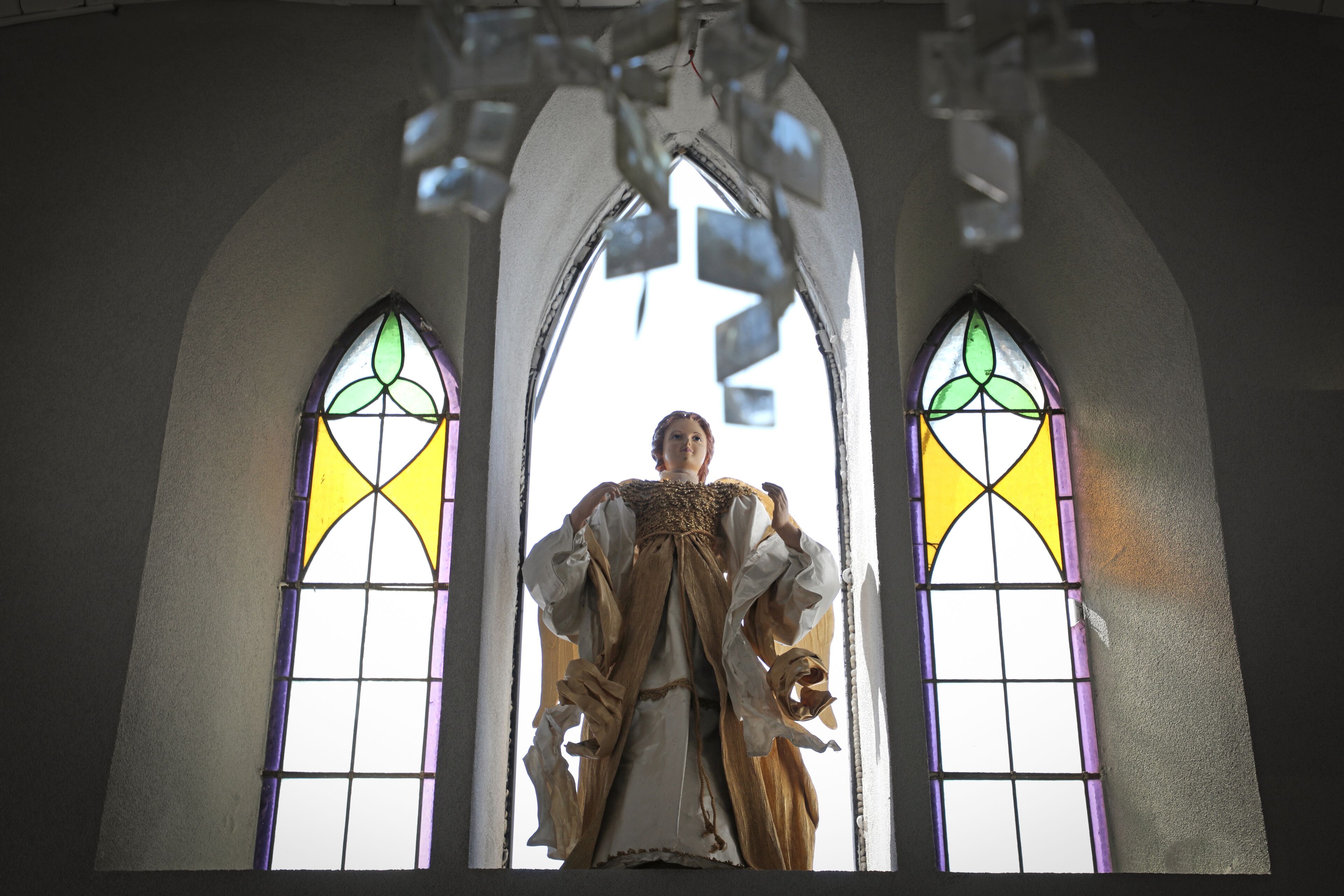 A statue in a church with stained glass windows.