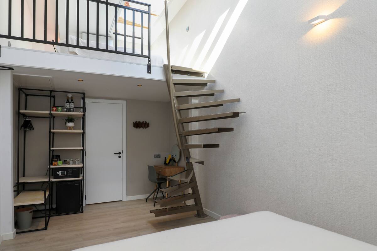 A modern interior with a spiral staircase, a dining area, and a small kitchen.