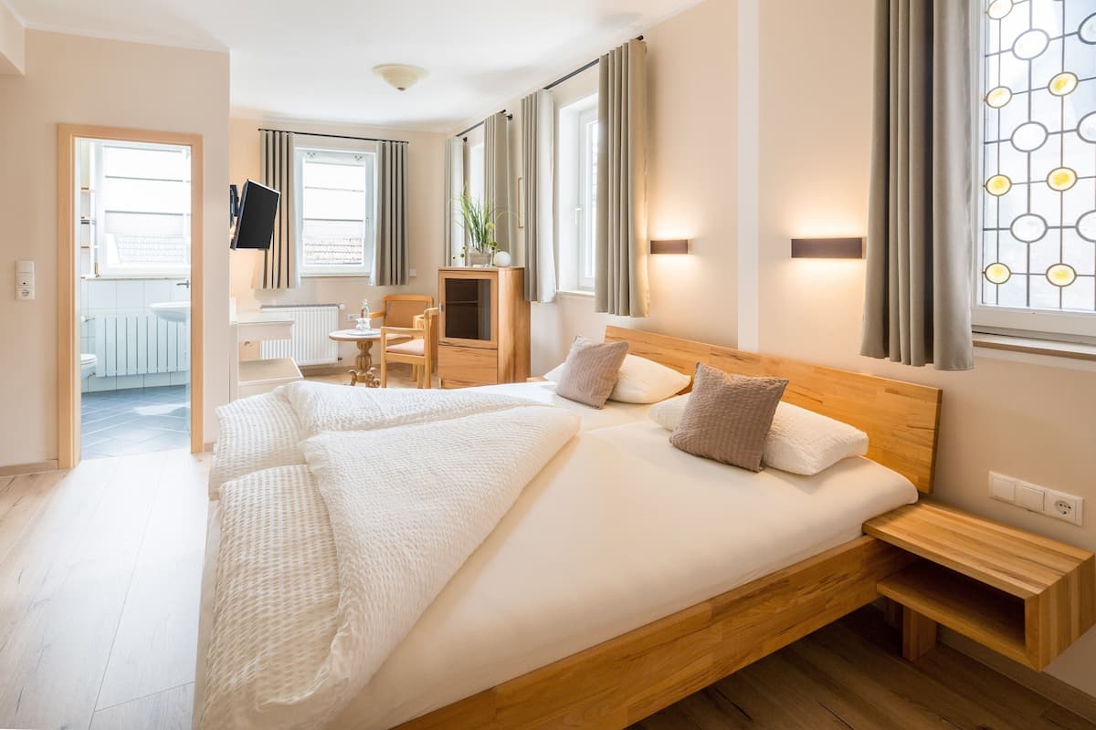 A modern hotel room with a large bed, a desk, and a view of the city.