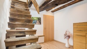 A wooden staircase with exposed beams, a wooden door, and a white vase with flowers. - Landhotel Löwen (Erlabrunn)
