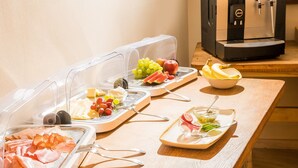 A buffet setup with various food items and a coffee machine. - Landhotel Löwen (Erlabrunn)