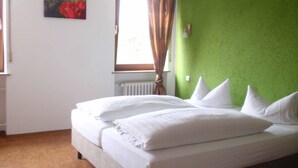Un dormitorio con cama, ventana con cortinas, radiador y pared verde.