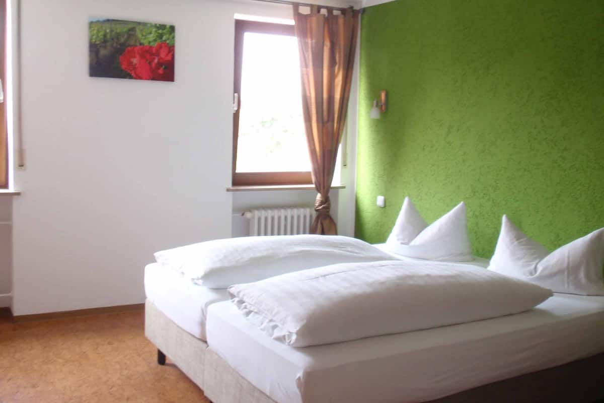 A bedroom with a bed, a window with curtains, a radiator, and a green wall.