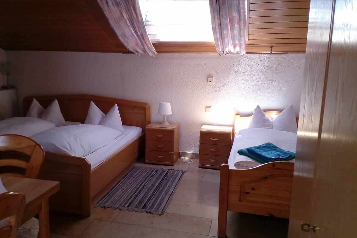 A bedroom with a wooden bed, bedside tables, a desk, and a chair.