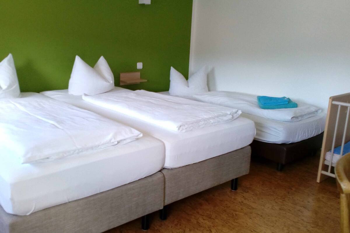A room with two single beds, a small table, and a chair.