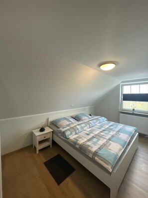 A bedroom with a bed, nightstand, and a window.