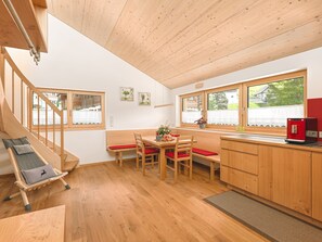 A modern kitchen with wooden cabinets, a dining area with a bench, and a staircase. - 2-room vacation apartment - Felder Apartments (Schoppernau)