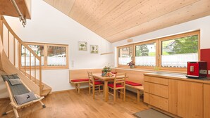 A modern kitchen with wooden cabinets, a dining area with a bench, and a staircase. - Vacation apartment 2 rooms - Felder Apartments (Schoppernau)