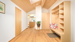 Un interno moderno con pavimento in legno, un lucernario, un'isola centrale con una pianta e scaffalature a muro.