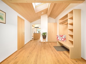 Ein modernes Interieur mit Holzboden, Oberlicht, einer zentralen Kochinsel mit Pflanze und eingebauten Regalen.
